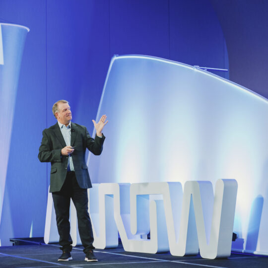 Conference keynote speaker on stage at Arrow Electronics event photographed by From the Hip Photo