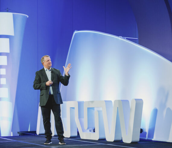 Conference keynote speaker on stage at Arrow Electronics event photographed by From the Hip Photo