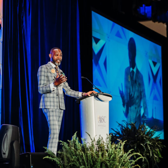 Professional conference headshot portrait with blue stage lighting background