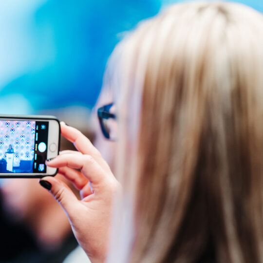 Conference attendee capturing speaker presentation on phone at Denver event