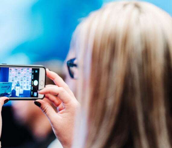 Conference attendee capturing speaker presentation on phone at Denver event