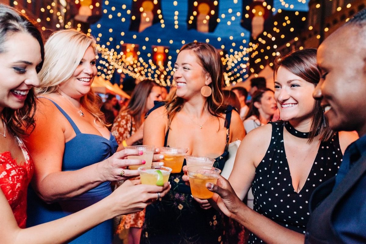 Women networking at conference reception with cocktails under string lights