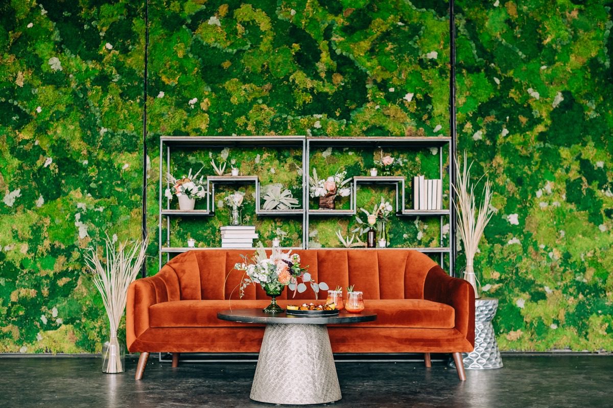 Styled expo booth lounge with velvet furniture and moss wall at trade show